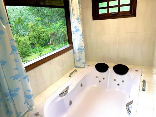 a bath tub in a bathroom with a window at Emy Pousada in Monte Verde
