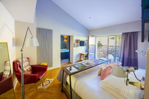 a bedroom with a large bed and a red chair at Le Florida Auberge contemporaine in Castéra-Verduzan