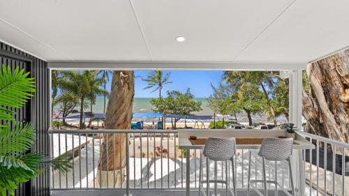 a balcony with a table and chairs on a beach at Absolute Beachfront Palm Cove Apt Sleeps 4 in Palm Cove