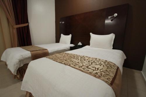 a hotel room with two beds with white sheets at Raoum Inn Majmaa in Al Majmaah