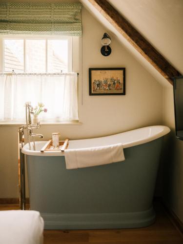 a bath tub in a bathroom with a window at The Black Horse in Amberley