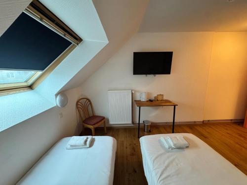 a attic room with two beds and a tv at Hôtel Arc-en-Ciel in Strasbourg