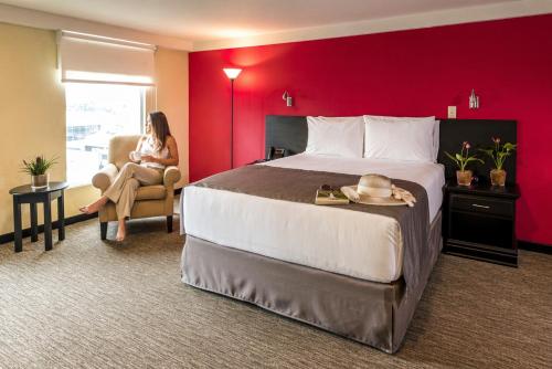 a woman sitting in a chair in a hotel room at Urban Green Hotel & Suites in San José