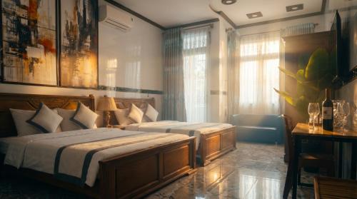 a bedroom with two beds and a couch and windows at CT Morning Hotel in Can Tho