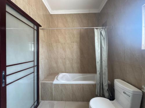 a bathroom with a toilet and a bath tub at Hotel Izzy Stay in Maputo