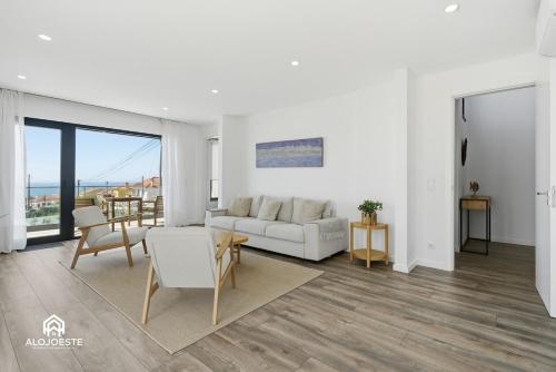 a living room with a white couch and a table at Mara Etxea - Villa with pool e Ocean View in Ericeira