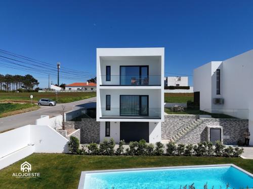 a white house with a swimming pool in front of it at Mara Etxea - Villa with pool e Ocean View in Ericeira
