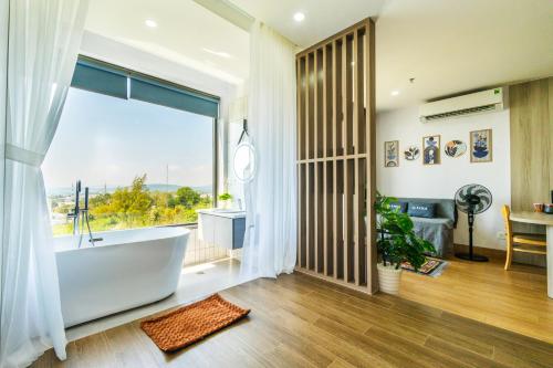 a bathroom with a tub and a large window at La Cheminee Boutique Apartment in Phú Quốc