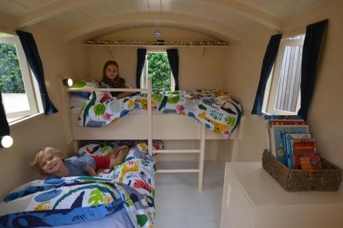 two children laying in beds in a tiny house at Isabelle Shepherd's hut in Hethersett