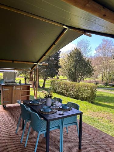 a table and chairs on a deck under a tent at Glamping Les Arpents Verts in Yvoir