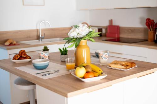 a kitchen counter with fruit and a vase of flowers at Grand Appartement 2 chambres et 2 SDB, Balnéo, Centre-ville in Quimper