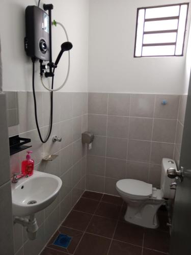 a bathroom with a white toilet and a sink at D'Suriah Homestay in Tanjung Karang