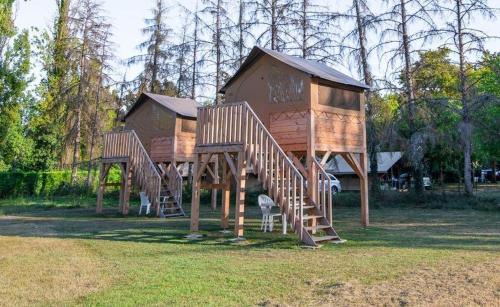 a tree house with stairs in a park at Camping Onlycamp Les Peupliers du Lac in Chindrieux