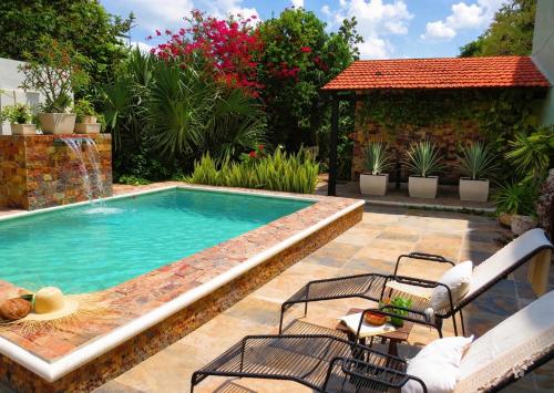 a swimming pool with two chairs and a table at Casa Magu Merida in Mérida