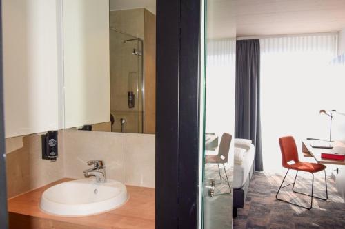 a bathroom with a sink and a room with a table at iQ-Hotel Ulm in Ulm