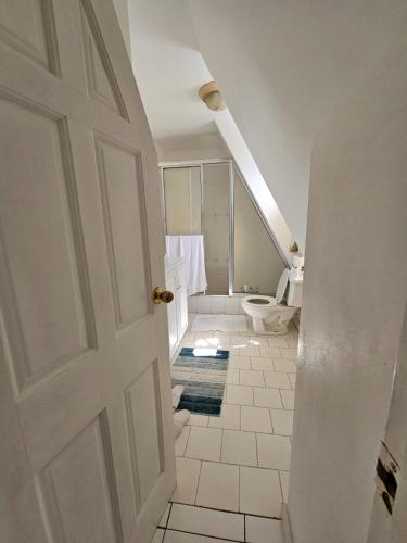 a white bathroom with a toilet and a door at Villa Nirvana II in Mount Irvine