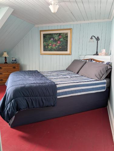 a large bed in a room with a red floor at Auberge Les Blancs Moutons in Saint-Laurent-de-l'ile d'Orleans