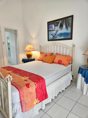 a bedroom with a white bed with orange pillows at Villa Nirvana II in Mount Irvine