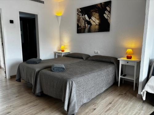 a bedroom with a bed and two tables with lamps at Carpe Diem Cadaqués in Cadaqués