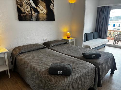 a bedroom with two beds and a chair and a window at Carpe Diem Cadaqués in Cadaqués