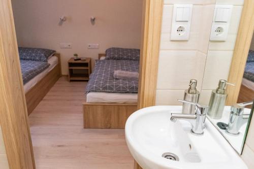 a bathroom with a sink and a mirror and a bed at Randevú Panzió in Sopron