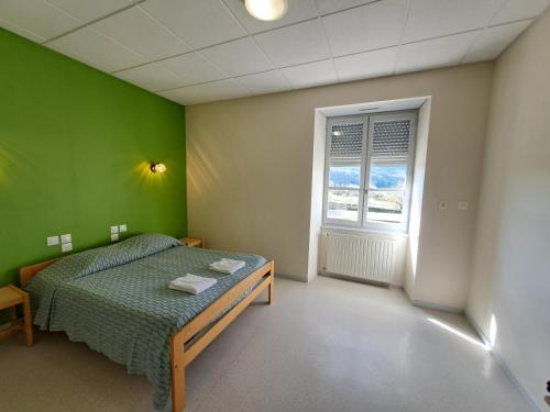 a green bedroom with a bed and a window at Accueil du Couvent de Malet in Saint-Côme-dʼOlt