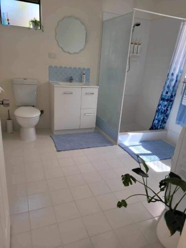 a white bathroom with a toilet and a shower at G & R Beach Cottage in Warnbro