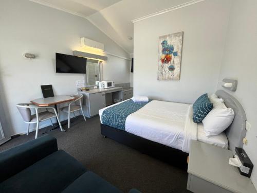 a hotel room with a bed and a desk and a table at Rest Point Motor Inn in Glen Innes