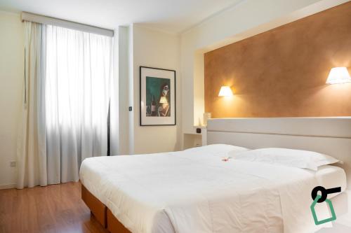 a bedroom with a large white bed and a window at Hotiday Brindisi Garibaldi in Brindisi