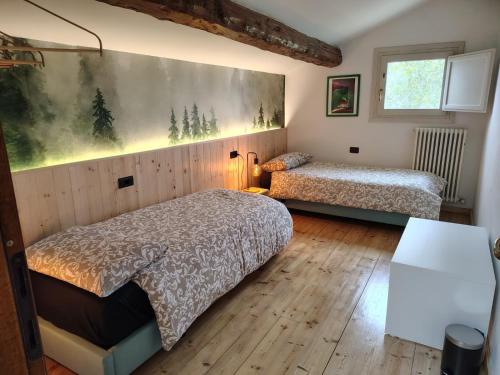 a bedroom with two beds and a painting on the wall at B&B Monte Adone in Santa Cecilia