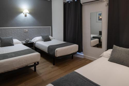 a hotel room with two beds and a mirror at Alda Centro Palencia in Palencia