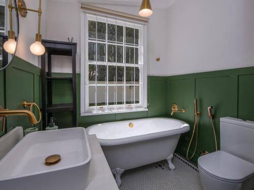a green bathroom with a tub and a toilet at House Erens By Die Bos in Stellenbosch