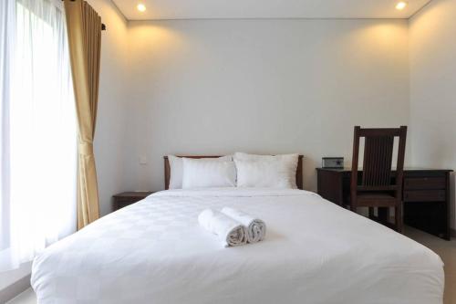 a bedroom with a white bed with towels on it at UmahOde Bali in Nusa Dua