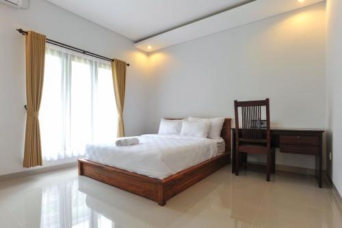 a bedroom with a bed and a chair and a desk at UmahOde Bali in Nusa Dua