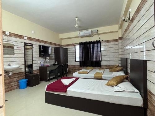 a bedroom with two beds and a sink and a desk at Hotel Yamunna Boarding and Lodgeing in Kollūru