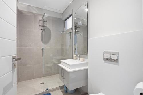 a white bathroom with a shower and a sink at Vista Zimbali in Ballito