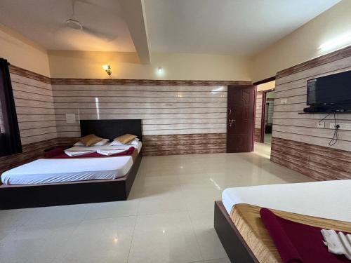 a bedroom with two beds and a flat screen tv at Hotel Yamunna Boarding and Lodgeing in Kollūru