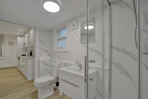 a white bathroom with a toilet and a shower at The Cozy Quarter in Bromley