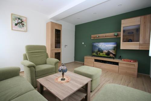 a living room with a couch and chairs and a tv at Gästehaus Hofmann - 4 Sterne Ferienwohnung Sorbitztal in Rohrbach