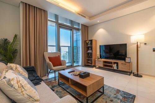a living room with a couch and a tv at Near Dubai Mall PoolAccess SunSetView KingBed in Dubai