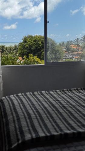 a bedroom with a bed and a window with a view at Chalé Almar - Praia do Sagi in Baía Formosa