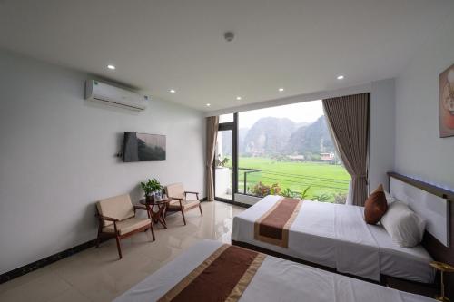 a bedroom with two beds and a large window at Tam Coc Sunshine Villa in Vũ Lâm
