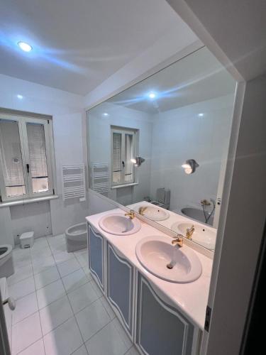 a white bathroom with two sinks and a mirror at Thalore room e apartments in Amantea