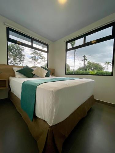 a bedroom with a large bed with two large windows at Casa Eucalipto in Chachagua