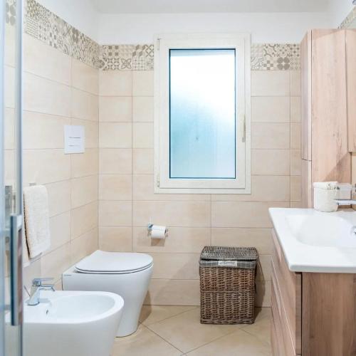 a bathroom with a toilet and a sink and a window at Domo Appeddu in Orosei
