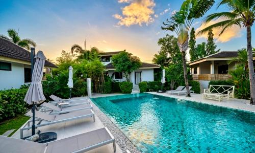 a swimming pool with chairs and umbrellas in front of a house at Tulum Villa Resort Koh Samui in Bophut