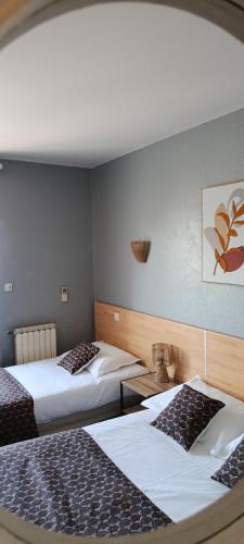 a room with two beds in a room at Hôtel Le Relais in Fleurance