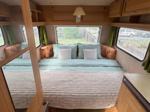 a bed in the back of a rv with two windows at Camping im Lammgarten in Volkach