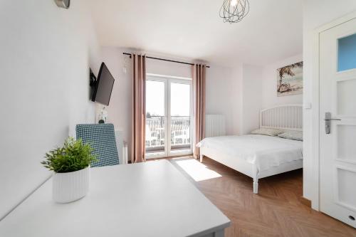 a white bedroom with a bed and a window at Pokoje Gościnne Dominika in Jastarnia