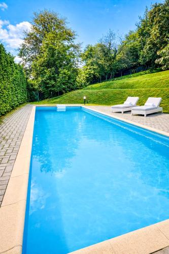 a swimming pool with two white lounge chairs next to it at Residenz Ai Ronchi in Germignaga